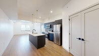 Located on Germantown Avenue in Philadelphia's 19144 neighborhood, this thoughtfully designed 2-bedroom, 2-bathroom residence offers a clean, contemporary aesthetic across a single floor. The open-concept kitchen and living area serves as the heart of the home, anchored by a sleek center island with a white quartz countertop and undermount sink. Dark navy cabinetry extends to the ceiling, complemented by a gray subway tile backsplash and a full suite of stainless steel appliances, including a refrigerator, electric range, and over-the-range microwave. Warm-toned hardwood-style flooring runs throughout the entire unit, creating a cohesive and inviting atmosphere. Pendant lighting with brass accents adds a refined touch above the island. Both bedrooms are bright and well-proportioned, featuring recessed lighting, large windows with blinds, and ample closet space. The unit includes three closets in total, providing generous storage throughout. The bathrooms are finished with light-toned tile flooring, a wood-vanity, and a striking tub-shower combination clad in floor-to-ceiling vertical blue tile with matte black fixtures. An in-unit laundry area adds everyday convenience. Clean white walls and recessed lighting throughout lend the space a fresh, move-in-ready feel.
