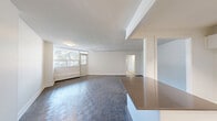 Located at 3122 Hurontario Street in Mississauga, this two-bedroom, one-bathroom unit offers a practical and well-organized layout across a single floor. The kitchen is outfitted with crisp white cabinetry, a herringbone tile backsplash, dark countertops, stainless steel appliances including a dishwasher, and light tile flooring — creating a clean, modern aesthetic. A peninsula counter provides additional workspace and separates the kitchen from the adjoining living area. The living room is generously proportioned, featuring patterned parquet-style flooring and a large window that brings in natural light and offers views of the tree-lined streetscape and city skyline beyond. Both bedrooms continue the parquet flooring and are brightened by windows overlooking greenery. The primary bedroom features floor-to-ceiling mirrored sliding closet doors, adding depth and functionality to the space. Baseboard heating units are present throughout the bedrooms. The bathroom includes a full tub-shower combination with tall grey tile surround, a toilet, and light tile flooring. A connecting hallway ties all rooms together efficiently. The unit's neutral colour palette and clean finishes create a bright, move-in-ready environment.