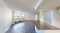 Located at 3122 Hurontario Street in Mississauga, this two-bedroom, one-bathroom unit offers a practical and well-organized layout across a single floor. The kitchen is outfitted with crisp white cabinetry, a herringbone tile backsplash, dark countertops, stainless steel appliances including a dishwasher, and light tile flooring — creating a clean, modern aesthetic. A peninsula counter provides additional workspace and separates the kitchen from the adjoining living area. The living room is generously proportioned, featuring patterned parquet-style flooring and a large window that brings in natural light and offers views of the tree-lined streetscape and city skyline beyond. Both bedrooms continue the parquet flooring and are brightened by windows overlooking greenery. The primary bedroom features floor-to-ceiling mirrored sliding closet doors, adding depth and functionality to the space. Baseboard heating units are present throughout the bedrooms. The bathroom includes a full tub-shower combination with tall grey tile surround, a toilet, and light tile flooring. A connecting hallway ties all rooms together efficiently. The unit's neutral colour palette and clean finishes create a bright, move-in-ready environment.