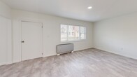 Located at 211 Summer St in Buffalo, NY, this two-bedroom, one-bathroom unit offers a clean, modern interior spread across a single floor. The space features a consistent light-toned tile flooring throughout, bright white walls, and recessed lighting that give every room a fresh, airy feel.

The kitchen is a standout feature, equipped with white shaker-style cabinetry extending to the ceiling, a white subway tile backsplash, light countertops, and a full suite of stainless steel appliances including a range, over-the-range microwave, dishwasher, and refrigerator. A window above the sink allows for natural light.

The living room is open and bright, with a large sliding glass door that leads directly to a private outdoor deck — a notable feature that brings in abundant natural light and outdoor access. A second bedroom features a wide triple-pane window overlooking the neighborhood, a built-in baseboard heater, and a louvered double-door closet.

The primary bedroom is a generously sized room with recessed lighting and ample space. The bathroom is clean and modern, featuring a full soaking tub with an overhead shower, white tile surround, chrome fixtures, and a grab bar. A connecting hallway ties all rooms together in a functional, straightforward layout.
