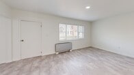 Located at 211 Summer St in Buffalo, NY, this two-bedroom, one-bathroom unit offers a clean, modern interior spread across a single floor. The space features a consistent light-toned tile flooring throughout, bright white walls, and recessed lighting that give every room a fresh, airy feel.

The kitchen is a standout feature, equipped with white shaker-style cabinetry extending to the ceiling, a white subway tile backsplash, light countertops, and a full suite of stainless steel appliances including a range, over-the-range microwave, dishwasher, and refrigerator. A window above the sink allows for natural light.

The living room is open and bright, with a large sliding glass door that leads directly to a private outdoor deck — a notable feature that brings in abundant natural light and outdoor access. A second bedroom features a wide triple-pane window overlooking the neighborhood, a built-in baseboard heater, and a louvered double-door closet.

The primary bedroom is a generously sized room with recessed lighting and ample space. The bathroom is clean and modern, featuring a full soaking tub with an overhead shower, white tile surround, chrome fixtures, and a grab bar. A connecting hallway ties all rooms together in a functional, straightforward layout.