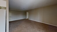 This single-floor unit at 1901 S Goyer Rd in Kokomo, Indiana, offers a practical and well-organized layout across three bedrooms and one bathroom. The galley-style kitchen is efficiently designed with white cabinetry lining both sides, light-toned laminate flooring, a double sink, ample counter space, and a full suite of appliances including an electric range, dishwasher, and refrigerator. A ceiling fan is visible from the kitchen, which opens toward the living area, creating a connected feel.

The living room is generously proportioned, finished with neutral-toned carpet and warm beige walls. A sliding glass door allows natural light to pour in and provides access to an outdoor area, enhancing the sense of openness. All three bedrooms feature the same neutral carpet and beige walls, maintaining a consistent aesthetic throughout. The primary bedroom includes a sliding-door closet with a built-in hanging rod. Additional bedrooms offer windows with outdoor views, bringing in natural light.

The bathroom features a full-size soaking tub with an overhead shower, a clean white surround with built-in shelving, and light wood-look flooring, delivering a simple and functional finish.