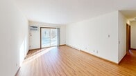 Located at 7733 Carrington Drive in Madison, WI, this single-floor apartment offers three bedrooms, two bathrooms, and a practical, efficiently laid-out floor plan. The living room features light wood-style flooring, bright white walls, and a sliding glass door that fills the space with natural light while providing outdoor views. A wall-mounted AC unit and baseboard heating ensure year-round comfort. The galley-style kitchen is well-appointed with warm oak cabinetry, dark granite countertops, a stainless steel refrigerator, and tile flooring — offering ample storage and prep space. The three bedrooms are carpeted for comfort, each benefiting from natural light through wood-trimmed windows. Two of the bedrooms include access to a shared closet with built-in shelving. The primary bedroom is a generously sized retreat. Two bathrooms serve the unit: one features a tiled tub-shower combination, an oak vanity with a stone-finish countertop, and tile flooring, while the second offers a similarly styled vanity with a large mirror and a bright vanity light fixture. A dedicated closet provides additional storage. Throughout, clean white walls and warm wood trim create a cohesive, neutral aesthetic.