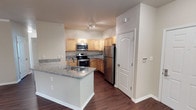 This single-floor unit offers a well-organized layout with distinct living, sleeping, and bathroom areas. The kitchen serves as a central highlight, featuring light maple cabinetry, granite countertops with subtle blue and gray veining, and a full suite of stainless steel appliances including an electric range, built-in microwave, and refrigerator. A peninsula with an integrated sink and additional counter space extends into the living area, enhancing both functionality and flow. Rich, dark hardwood-style flooring runs throughout the kitchen and bathrooms, adding warmth and visual continuity.

The bedrooms are carpeted in neutral tones and receive natural light through blinded windows. Ceiling fans provide comfort, and closet options range from standard reach-ins to a generously sized walk-in with multi-tiered wire shelving. The primary bathroom features a long dual-sink granite vanity with light maple cabinetry, a tub-shower combo, and a window that introduces natural light. A secondary full bathroom includes a granite-topped vanity and a tub-shower combination. Throughout the unit, neutral wall tones and clean white trim create a cohesive, move-in-ready aesthetic.