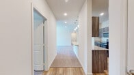 This single-floor residence offers a thoughtfully designed open-concept layout that seamlessly connects the living, dining, and kitchen areas. A wide hallway with recessed lighting and warm wood-look flooring welcomes you into the space, offering an immediate sense of openness and flow.

The kitchen is a standout feature, equipped with a full suite of stainless steel appliances, including a refrigerator, electric range, and over-the-range microwave. Rich, dark wood cabinetry pairs elegantly with light granite countertops, providing ample storage and prep space. A peninsula with an integrated sink extends into the living area, making it ideal for casual dining or entertaining. Distinctive pendant lights hang above the peninsula, adding a modern touch.

The living area is generously proportioned, featuring plush neutral carpeting that extends into the bedrooms. Arched doorways add an architectural detail that softens the overall aesthetic. The bedrooms are well-sized, each with carpet flooring, natural light from windows with blinds, and ceiling fans for added comfort.

The bathrooms are finished with the same granite countertops and dark wood cabinetry found in the kitchen, maintaining a cohesive design throughout. Each bathroom includes a shower/tub combination and wood-look tile flooring, lending a clean and contemporary feel to the space.