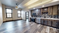 This thoughtfully designed 2-bedroom, 2-bathroom residence delivers a contemporary urban living experience across a single, well-appointed floor. The open-concept layout seamlessly connects the kitchen and living area, creating a spacious and functional common space. The kitchen is a standout feature, showcasing rich dark wood cabinetry, a mosaic tile backsplash, stainless steel appliances including a range, microwave, dishwasher, and refrigerator, plus a built-in wine rack that adds a stylish touch. Wood-look luxury vinyl plank flooring flows throughout the entire residence, lending warmth and visual continuity. The primary bedroom is generously sized, featuring dual windows that frame city views and fill the room with natural light. The second bedroom also enjoys an urban outlook through its own window. Each bedroom benefits from dedicated closet space. Both bathrooms are finished to a high standard, featuring wood-toned vanities with white countertops, matte black fixtures, and white subway tile shower surrounds. Sliding barn-style doors add a modern design element to one bathroom entry. Neutral gray-toned walls and dark window trim create a cohesive, contemporary aesthetic throughout the entire space.