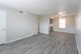 Located at 5301 Woodrow Bean Transmountain Dr in El Paso, Texas, this single-story unit offers a cohesive, updated interior with a neutral color palette and light wood-look flooring that flows consistently throughout the space. The design emphasizes clean lines and a bright, airy atmosphere.

The main living area is generously proportioned, featuring a ceiling fan, window with blinds for natural light control, and a textured ceiling. The open feel of the room provides versatile layout options. An additional room, similarly finished with wood-look flooring, a ceiling fan, and a window with blinds, functions well as a bedroom or flexible-use space.

The kitchen is well-appointed with gray cabinetry, white subway tile backsplash, light countertops, a double-basin stainless steel sink, and black appliances including a full-size refrigerator. The wood-look flooring continues here, maintaining visual consistency.

The bathroom features a full-size tub-shower combo with a bright white surround and clean fixtures. Throughout the unit, white baseboards and neutral gray walls contribute to a polished, move-in-ready finish. Windows fitted with horizontal blinds allow for adjustable natural light in every room.