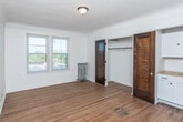 Located at 130 Glynn Ct in Detroit's vibrant 48202 corridor, this single-floor unit blends classic architectural character with functional living spaces. Rich hardwood floors run throughout, lending warmth and continuity to every room.

The living and sleeping areas are generously proportioned, bathed in natural light through large double-hung windows that offer pleasant outdoor views. Deep-toned wood doors with glass panels add a timeless, vintage charm, while crown molding details reinforce the unit's period character. Radiator heating units are present in the bedrooms, a hallmark of classic Detroit residential architecture.

A spacious bedroom features a full-width closet with a hanging rod and upper shelf, providing ample storage. An additional room with double windows offers flexibility as a second bedroom or living area.

The kitchen is efficiently laid out with white cabinetry, subway tile backsplash, a butcher-block countertop, a stainless steel refrigerator, and a gas range — all complemented by hardwood flooring that carries through from the main living spaces. A distinctive arched doorway connects the kitchen area to the rest of the unit, adding architectural interest.

The bathroom is clean and well-appointed, featuring a tub/shower combination with a glass door, a toilet, and a wall-mounted sink, finished with wood-tone flooring.