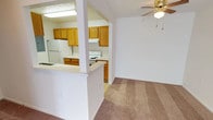 This single-floor residence offers a practical and comfortable layout designed for easy everyday living. The open-concept design connects the living area to the kitchen via a pass-through counter, creating a sense of openness and flow between the two spaces. The kitchen is well-appointed with warm honey-toned cabinetry lining both sides of the galley-style layout, white appliances including a refrigerator, electric range, and dishwasher, along with ample counter space and a stainless steel sink. Light tile flooring and overhead fluorescent lighting keep the kitchen bright and functional.

The living area is generously sized, featuring wall-to-wall carpet in a neutral tan tone and a ceiling fan with a light fixture. Large sliding glass doors flood the space with natural light and offer access to the outdoors. An additional carpeted bedroom is equally well-lit, with its own ceiling fan, a window for natural light, and multiple closets providing excellent storage.

The full bathroom is clean and efficient, featuring a tub-shower combination, a toilet, and a vanity with a wood-toned cabinet and a well-lit mirror above. Throughout the unit, neutral wall tones and consistent carpeting create a cohesive, move-in-ready atmosphere suited for a variety of living arrangements.