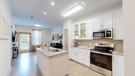 Located at 1133 West Baltimore Pike in Media, PA, this single-floor residence offers a thoughtfully designed layout across two bedrooms and two bathrooms. The open-concept kitchen and living area serves as the heart of the home, featuring white shaker cabinetry, granite countertops, a center island with sink, stainless steel appliances including a dishwasher and range, and a tasteful tile backsplash. Light wood-style flooring flows throughout the main living areas, complementing the bright, neutral palette and recessed lighting overhead. The living room is airy and welcoming, with natural light streaming through large windows fitted with blinds. Both bedrooms are carpeted and include ceiling fans, with the primary bedroom offering a generous footprint and natural light. Each bathroom is finished with granite-topped white vanities and large-format tile flooring. One bathroom features a tub and shower combo adorned with marble-style tile surround, while the second provides a clean, efficient layout. A dedicated laundry room houses a full-size washer and dryer. A hallway with closet storage connects the rooms, completing this well-organized and modern living space.