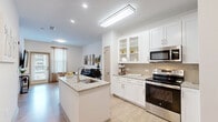 Located at 1133 West Baltimore Pike in Media, PA, this single-floor residence offers a thoughtfully designed layout across two bedrooms and two bathrooms. The open-concept kitchen and living area serves as the heart of the home, featuring white shaker cabinetry, granite countertops, a center island with sink, stainless steel appliances including a dishwasher and range, and a tasteful tile backsplash. Light wood-style flooring flows throughout the main living areas, complementing the bright, neutral palette and recessed lighting overhead. The living room is airy and welcoming, with natural light streaming through large windows fitted with blinds. Both bedrooms are carpeted and include ceiling fans, with the primary bedroom offering a generous footprint and natural light. Each bathroom is finished with granite-topped white vanities and large-format tile flooring. One bathroom features a tub and shower combo adorned with marble-style tile surround, while the second provides a clean, efficient layout. A dedicated laundry room houses a full-size washer and dryer. A hallway with closet storage connects the rooms, completing this well-organized and modern living space.