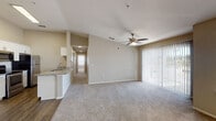 Located at 200 Village Blvd in Davenport, Florida, this single-story unit offers a well-designed, open-concept floor plan that seamlessly connects the main living areas. The spacious living room features vaulted ceilings, plush carpeting, a ceiling fan, and large sliding glass doors with vertical blinds that invite natural light and provide access to the outdoors. The kitchen is well-appointed with white shaker-style cabinetry, granite countertops, a subway tile backsplash, and a full suite of stainless steel appliances including a range, over-the-range microwave, and refrigerator. A granite-topped breakfast bar connects the kitchen to the adjoining dining and living areas. Wood-look vinyl flooring runs through the kitchen and entry areas, creating a clean contrast with the carpeted rooms. The bedrooms are generously sized, each with ceiling fans, ample natural light from windows with blinds, and vaulted ceilings. The bathrooms are finished with granite-topped white vanities, framed mirrors, and wood-look flooring — one featuring a tub/shower combo and another a walk-in shower. A dedicated in-unit laundry space includes a full-size washer and dryer with overhead shelving for added convenience.