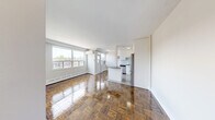 Located at 82 Warren Rd, Suite 505, in the heart of midtown Toronto, this two-bedroom, one-bathroom unit offers a well-designed layout across a single floor. The kitchen is a standout feature, boasting white shaker-style cabinetry reaching to the ceiling, a light grey subway tile backsplash, dark countertops, and a full suite of stainless steel appliances including a dishwasher, electric range, and French door refrigerator. A peninsula with matching dark countertop provides additional prep space and separates the kitchen from the adjoining living area, which features warm, richly toned parquet hardwood flooring throughout. Both bedrooms are comfortably sized and filled with natural light from large windows that frame views of the surrounding midtown neighbourhood. The primary bedroom includes mirrored sliding closet doors, while the second bedroom benefits from a classic radiator and an open, airy feel. The bathroom is finished with clean white subway tile wrapping the full tub-shower surround, chrome fixtures, and a dark-toned vanity with an integrated sink. A hallway connects all rooms efficiently, completing this functional and attractively finished urban residence.