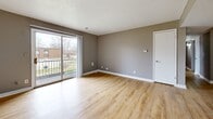 Located at 2100 N 57th St in Kansas City, KS, this single-floor unit offers four bedrooms, one bathroom, and a dedicated closet across a well-organized layout. Consistent light wood laminate flooring and neutral warm gray walls flow throughout the space, creating a cohesive and clean aesthetic. Textured ceilings and crisp white trim complement the understated color palette in every room.

The primary bedroom is the most spacious of the four, featuring sliding glass doors that open onto a private balcony with outdoor views — a standout feature that brings in generous natural light. The remaining three bedrooms each include windows with blinds that allow for natural light while maintaining privacy; each room offers a practical, versatile footprint suitable for various configurations.

The single full bathroom is straightforward and functional, equipped with a full-size soaking tub and shower combination with clean white surround panels. A dedicated closet space with wood flooring provides additional storage. Hallways connect the rooms efficiently, supporting a logical flow throughout the unit.

The kitchen area, visible in the floorplan, is situated at one end of the layout. Overall, the space presents a clean, move-in ready environment with consistent finishes and practical room distribution throughout.