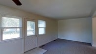 This two-floor home offers a straightforward and functional layout designed for comfortable everyday living. The entryway greets visitors with tile flooring and a classic paneled front door flanked by windows that invite an abundance of natural light into the space. Just beyond the entry, the main living area transitions to wall-to-wall carpeting, creating a warm and comfortable atmosphere. The walls are finished in a clean, neutral tone throughout, providing a versatile backdrop suited to a variety of interior styles. The windows are fitted with blinds, offering practical light control while maintaining a tidy appearance. Flush with the wall, floor vents indicate a forced-air climate system to keep the home comfortable year-round. The open feel of the main level is enhanced by smooth ceilings and simple, uncluttered lines that give the space a bright and airy quality. Spanning two floors, the home provides a clear separation between living and private spaces, with the upper level offering additional room for bedrooms or auxiliary uses. Overall, the property presents a clean, move-in ready environment with timeless, understated finishes throughout.