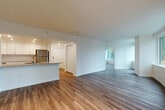 Located at 700 Virginia St in the heart of Seattle, WA, this one-bedroom, two-bathroom apartment offers a well-designed layout across a single floor. The open-concept living, dining, and kitchen area creates a spacious, connected feel, anchored by warm hardwood-style flooring throughout. Large, curved windows in the living area flood the space with natural light and frame dynamic views of Seattle's urban skyline.

The kitchen is outfitted with crisp white shaker cabinetry, granite countertops, a subway tile backsplash, and a full suite of stainless steel appliances including a refrigerator, range, microwave, and dishwasher. A peninsula provides additional prep space and casual dining.

The bedroom features track lighting, a large window with city views, and direct access to a full bathroom complete with a tiled tub/shower surround, granite vanity, and marble-style tile flooring. A second bathroom off the main living area mirrors the same clean, modern finishes. Four closets throughout the unit provide generous storage. The entrance leads smoothly into the main living spaces, enhancing the overall flow. Neutral tones, recessed lighting, and contemporary finishes give the entire unit a bright, polished ambiance.