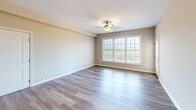 This single-floor, 2-bedroom, 2-bathroom residence in Roanoke, Virginia offers a thoughtfully designed layout that balances comfort and functionality. The open-concept kitchen and living area serves as the heart of the home, featuring rich dark wood cabinetry, light countertops, stainless steel appliances including a range, microwave, and refrigerator, and a peninsula with pendant lighting that connects seamlessly to the living space. Light wood-style flooring runs throughout the main living areas, complemented by a ceiling fan overhead. A glass-paneled door in the living area leads to an outdoor deck, while large windows allow generous natural light throughout. Both bedrooms are carpeted and include ceiling fans, with the primary bedroom offering notable space and direct access to a walk-in closet equipped with wire shelving. The second bedroom also benefits from a large window with outdoor views. Two full bathrooms each include a tub-shower combination, with one featuring warm wood-toned cabinetry and wood-style flooring. A dedicated laundry area with a stacked washer and dryer provides added convenience. A connecting hallway ties all rooms together in an efficient, well-organized floor plan.