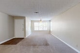 Located at 4355 Cascade Rd SW in South Fulton, Georgia, this single-floor home offers a practical and comfortable layout designed for easy living. The spacious living area greets you at the entry, featuring neutral-toned carpet, a textured ceiling, a ceiling fan, and a large front-facing window that invites generous natural light and views of the surrounding greenery. The open floor plan flows seamlessly into a secondary living or dining area, also carpeted, which connects directly to the kitchen via a pass-through counter. The galley-style kitchen is well-appointed with dark cabinetry, granite-style countertops, a stainless sink, and black appliances including a refrigerator, range, and dishwasher. Wood-look flooring adds warmth to the kitchen and extends toward a hallway leading to additional rooms. The bedroom is a comfortable, carpeted retreat with a large window offering ample natural light. The bathroom features a wide vanity with granite-style countertops, dark cabinetry, a full mirror, and a shower-tub combination. Throughout the home, neutral wall tones and consistent finishes create a cohesive and move-in-ready atmosphere.