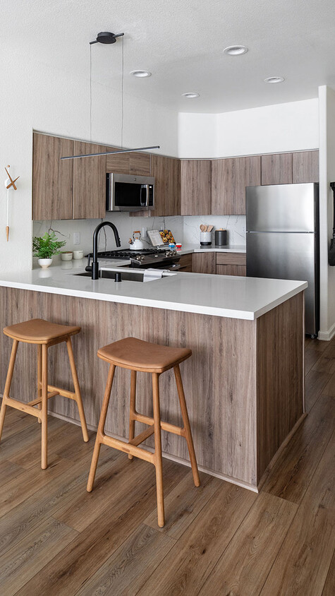 Cocina del apartamento con electrodomésticos de acero inoxidable, encimeras de cuarzo y pisos de madera. - Griffis Mission Valley