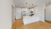 Located at 223 Long Shoals Rd in Asheville, NC, this well-designed 3-bedroom, 2-bathroom unit offers a clean, modern aesthetic across a single thoughtfully laid-out floor. Light hardwood flooring flows consistently throughout the space, creating a cohesive and airy feel.

The kitchen is a standout feature, showcasing white shaker cabinetry with matte black hardware, a classic subway tile backsplash, and quartz countertops. A central island with a built-in sink and pendant lighting above adds both functionality and style, complemented by a full suite of stainless steel appliances.

The three bedrooms are bright and well-proportioned, each equipped with a ceiling fan and multiple windows fitted with blinds that allow for ample natural light. The primary bedroom includes access to a spacious walk-in closet outfitted with wrap-around shelving and hanging rods.

The primary bathroom features a dual-sink vanity with quartz countertops, matte black fixtures, framed mirrors, and stylish sconce lighting. The second bathroom offers a tub-shower combination with tile surround. Throughout the unit, Shaker-style interior doors with matte black hardware maintain a consistent modern design language.