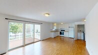 This two-floor home offers a practical and well-organized layout designed for comfortable everyday living. The main level features an open-plan living and dining area with warm hardwood-style flooring that flows seamlessly into the kitchen. The kitchen is equipped with white cabinetry, ample counter space, a double sink, a dishwasher, and a range, all finished with neutral tones that create a clean and inviting atmosphere. Sliding glass doors lead directly from the living area to an outdoor deck, bringing in generous natural light and providing easy access to the exterior. A convenient half bathroom is also located on this level. The lower level includes a spacious, open room with hardwood-style flooring, offering flexible use as a family room or recreation space, along with access to a sizable attached two-car garage. The upper floor hosts multiple carpeted bedrooms, each featuring ceiling fans and windows that allow for natural light and outdoor views. Two full bathrooms serve the upper level, each outfitted with a vanity, toilet, and a combined tub and shower. Throughout the home, white walls and neutral finishes contribute to a bright, clean aesthetic that is easy to personalize.