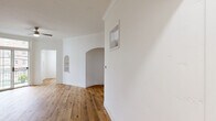 Located at 861 Fedora St in the heart of Los Angeles, this single-floor residence showcases a thoughtfully designed interior that blends classic architectural charm with modern finishes. Warm-toned hardwood flooring runs consistently throughout the entire space, creating a cohesive and inviting atmosphere from room to room.

The living area is a standout, highlighted by elegant arched doorways and a built-in arched shelving niche that adds architectural character to the bright white walls. Crown molding frames the ceilings throughout, lending a refined, traditional touch. A ceiling fan provides comfort, while large glass doors open to a balcony, flooding the space with natural light and offering views of the surrounding neighborhood.

The kitchen is clean and functional, outfitted with white shaker-style cabinetry, light countertops, and a stainless steel gas range, offering a practical and attractive cooking environment.

The bathroom continues the home's crisp, white aesthetic with a single-vanity and mirror, a full soaking tub with shower, and a window that brings in natural light. Additional spaces include a utility or laundry area with dedicated wall access points. Throughout the residence, the consistent use of white walls and natural wood flooring creates a bright, airy ambiance well-suited to Los Angeles living.