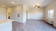 Located at 7545 Sunwood Dr NW in Ramsey, Minnesota, this single-floor unit offers a thoughtfully designed layout that maximizes every square foot. The open living area features neutral-toned walls, durable luxury vinyl plank flooring, and a ceiling fan with integrated lighting, creating a bright and comfortable atmosphere. An electrical panel is conveniently integrated into the living space wall, and clean white trim and panel-style doors contribute to a modern, cohesive aesthetic throughout.

The kitchen is a standout feature, outfitted with grey shaker-style cabinetry, black hardware accents, and crisp white countertops. A full suite of stainless steel appliances includes an electric range, over-the-range microwave, refrigerator, and dishwasher. A subway tile backsplash adds a clean, contemporary touch, while the light wood-toned flooring flows seamlessly from the living area into the kitchen.

The bathroom is well-appointed with a wide vanity featuring grey cabinetry, black hardware, and a white countertop with an undermount sink. A large mirror, matte black towel bar, and wood-look tile flooring round out the space with a modern farmhouse sensibility. A closet provides additional storage. The unit also includes a walk-in shower/tub area, completing this efficiently designed home.