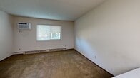 Located at 4821 Westchester Dr in Youngstown, Ohio, this single-floor unit offers a straightforward and functional layout. The kitchen is well-equipped, featuring dark wood cabinetry extending to the ceiling for generous storage, white appliances including an electric range and refrigerator, a double-basin sink, and durable tile-patterned flooring. An overhead range hood and under-cabinet space add to the kitchen's practicality. A solid wood entry door leads directly into the kitchen area, providing convenient access.

The living and sleeping areas are finished with wall-to-wall carpeting in a neutral tone, complemented by crisp white walls and dark baseboards that provide clean visual contrast. A window fitted with blinds allows natural light to filter in while offering a view of the surrounding greenery outside.

The bathroom is accessed through a solid wood door and features classic tile flooring in a small mosaic pattern, a vanity with white cabinetry and a single-basin sink, a mirrored medicine cabinet with overhead lighting, and a toilet. A grab bar and overhead ventilation are also present, adding functionality to the space.

Overall, the unit presents a practical and straightforward interior, offering a solid foundation for those seeking a functional living space in the Youngstown area.