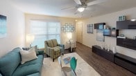This single-floor residence offers a thoughtfully designed layout that balances comfort and functionality across its multiple rooms. The open living area serves as the heart of the home, featuring wood-style flooring, a ceiling fan, and large windows fitted with blinds that invite an abundance of natural light. The space is warm and inviting, with neutral wall tones that complement the teal-accented décor carried consistently throughout the home.

The galley-style kitchen is efficiently designed with ample cabinetry, granite-style countertops, a stainless steel sink, and black appliances including a refrigerator, range, and microwave. The layout maximizes counter and storage space, making it highly functional for everyday use.

Each bedroom is carpeted and features ceiling fans, neutral walls, and windows providing natural light. The bedrooms offer generous proportions, with closet access visible in several rooms, providing practical storage solutions.

The bathrooms are finished with granite-style countertops, wood-style flooring, and large mirrors above the vanities. One bathroom includes a shower/tub combination, while the other offers a spacious vanity with dual mirrors. Both are clean and well-appointed. Overall, the residence presents a cohesive, comfortable living environment with consistent finishes throughout.