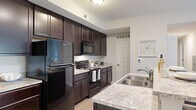 Located in Sunbury, Ohio, this single-floor, three-bedroom, two-bathroom home offers a well-designed layout with a functional open-concept living area. The kitchen is a standout feature, showcasing rich dark cabinetry, granite-style countertops, and black Whirlpool appliances including a refrigerator, electric range, and over-range microwave. A central kitchen island with a double stainless steel sink and bar seating provides an ideal casual dining or entertaining space. Light wood-style flooring runs through the kitchen and living areas, creating a clean, cohesive aesthetic.

The living room is bright and welcoming, with natural light streaming in through a sliding glass door that opens to an outdoor view. Neutral walls and plush carpeting give the space a warm, comfortable feel.

The primary bedroom offers a calm retreat with soft carpet, neutral tones, natural light from a window, and two reach-in closets providing ample storage. Additional bedrooms maintain the same understated, cozy character. Each bathroom is finished with stone-tile flooring, dark wood vanities, granite-topped sinks, and clean white fixtures. One bathroom features a glass-enclosed shower, while the other offers a more compact, functional design. A connecting hallway ties all rooms together in this efficiently arranged home.