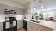 Located at 3333 Weslayan St in Houston's desirable 77027 zip code, this thoughtfully designed one-bedroom, one-bathroom residence offers a smart, efficient layout across a single floor. Light wood-tone flooring flows throughout, complementing a clean, modern aesthetic anchored by crisp white walls.

The kitchen is a standout feature, showcasing gray shaker-style cabinetry, white subway tile backsplash, white quartz countertops, and black appliances including a range, built-in microwave, and dishwasher. A stainless steel refrigerator and pendant lighting above the sink add polished finishing touches. The kitchen opens toward the living area, creating a connected, sociable flow.

The living room is bright and inviting, with a large window dressed in sheer curtains that invite natural light while offering outdoor views. The bedroom is a comfortable retreat, featuring a ceiling fan, a generous window, and light hardwood-style flooring. A dedicated closet and hallway provide practical storage solutions.

The bathroom is finished with large-format gray tile flooring, subway-tiled tub surround, and gray vanity cabinetry with white countertops. A convenient in-unit laundry closet houses a full-size washer and dryer. The entry hallway provides a welcoming transition into the home.