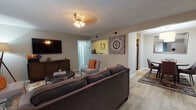 Located at 420 N Dean Rd in Auburn, Alabama, this single-floor residence offers a thoughtfully organized layout with distinct living, dining, kitchen, bedroom, and bathroom areas. The living room serves as the heart of the home, featuring light wood-look flooring, a textured ceiling, a ceiling fan with lighting, and a large sliding door with vertical blinds that allows natural light to fill the space. The dining area is positioned adjacent to the living room and is highlighted by a statement pendant light and a round dining table with seating for four. The kitchen is equipped with stainless steel appliances, including an electric range and over-the-range microwave, complemented by granite-look countertops, gray cabinetry, and a classic subway tile backsplash. The bedrooms are carpeted for comfort, featuring neutral wall tones and ample space for furnishings. The bathroom is clean and functional, offering a tub-shower combination, dark wood vanity with granite-look countertop, and wood-look tile flooring. Throughout the residence, a consistent neutral color palette and modern finishes create a cohesive, welcoming ambiance suitable for everyday living.