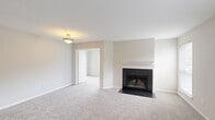 Located at 3340 Hampton Point Drive in Silver Spring, Maryland, this two-bedroom, one-bathroom unit offers a well-organized single-floor layout designed for comfortable everyday living. The living room serves as the heart of the home, featuring a classic fireplace with a white mantel and dark surround, soft carpeting underfoot, and multiple windows that fill the space with natural light and views of the surrounding greenery.

The kitchen is equipped with warm wood cabinetry, dark granite countertops, a double stainless steel sink, and white appliances including a range, built-in microwave, and refrigerator. Hardwood-style flooring runs throughout the kitchen, adding a clean, practical finish.

Both bedrooms are carpeted and bright, each featuring ceiling fans and windows with blinds that allow for natural light and outdoor views. The primary bedroom includes a sliding-door closet, while the second bedroom offers a similarly comfortable and airy feel.

The bathroom features hardwood-style flooring, a granite-topped vanity, and a full tub-shower combination with white tile surround. A stacked washer and dryer unit is conveniently located within the bathroom, adding in-unit laundry functionality. A hallway connects all rooms, completing this practical and inviting layout.