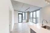 Located on the 18th floor of a contemporary high-rise in Chicago's South Loop, this two-bedroom, two-bathroom unit offers a modern urban living experience with striking architectural details. Exposed concrete ceilings and structural columns lend an industrial character throughout, while light wood-look flooring provides warmth and continuity across the open layout. The combined kitchen and living area serves as the heart of the unit, where floor-to-ceiling windows and a glass balcony door frame sweeping city views and flood the space with natural light. The kitchen is outfitted with dark wood cabinetry, a mosaic tile backsplash, stainless steel appliances including a gas range and French door refrigerator, and a large island with an integrated sink and generous counter space. Both bedrooms feature the same exposed concrete ceilings and large windows with city views, and include closet storage. The bathrooms are finished with clean, neutral tilework — one featuring a walk-in glass-enclosed shower with large-format ceramic tile surround and a sleek chrome fixture. A dark wood vanity with ample drawer storage completes the bathrooms. The overall aesthetic is a cohesive blend of industrial and contemporary design, well-suited for those seeking a polished Chicago high-rise lifestyle.