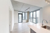 Located on the 18th floor of a contemporary high-rise in Chicago's South Loop, this two-bedroom, two-bathroom unit offers a modern urban living experience with striking architectural details. Exposed concrete ceilings and structural columns lend an industrial character throughout, while light wood-look flooring provides warmth and continuity across the open layout. The combined kitchen and living area serves as the heart of the unit, where floor-to-ceiling windows and a glass balcony door frame sweeping city views and flood the space with natural light. The kitchen is outfitted with dark wood cabinetry, a mosaic tile backsplash, stainless steel appliances including a gas range and French door refrigerator, and a large island with an integrated sink and generous counter space. Both bedrooms feature the same exposed concrete ceilings and large windows with city views, and include closet storage. The bathrooms are finished with clean, neutral tilework — one featuring a walk-in glass-enclosed shower with large-format ceramic tile surround and a sleek chrome fixture. A dark wood vanity with ample drawer storage completes the bathrooms. The overall aesthetic is a cohesive blend of industrial and contemporary design, well-suited for those seeking a polished Chicago high-rise lifestyle.