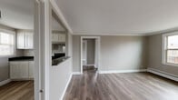 Located on Chatsworth Ave in Buffalo, NY, this 2-bedroom, 1-bathroom unit offers a practical and well-appointed single-floor layout. Warm hardwood-style flooring runs throughout the main living areas, complemented by neutral taupe walls and crisp white trim that create a clean, cohesive aesthetic. The combined living and dining area is open and airy, featuring a pass-through window that connects to the kitchen, enhancing the sense of flow between spaces. The kitchen is equipped with white shaker-style cabinetry, dark granite countertops, a black appliance package including a refrigerator and range, and a window that brings in natural light. Both bedrooms feature the same hardwood-style flooring, baseboard heating, and generous closet storage. The primary bedroom is comfortably sized and includes double closets, while the second bedroom benefits from two windows with neighborhood views. The bathroom is finished with large-format dark slate-style wall tile, grey floor tile, a soaking tub, and a bright window for ventilation. A hallway connects the rooms efficiently, and four closets throughout the unit provide ample storage for everyday living.