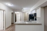 Located in the heart of Edmonton at 10803 Jasper Ave NW, this well-appointed 2-bedroom, 2-bathroom unit offers a thoughtfully designed open-concept layout that maximizes every square foot. The combined living, dining, and kitchen area forms the heart of the home, anchored by a sleek kitchen featuring white cabinetry, granite stone countertops, a tile backsplash, and a full suite of black appliances including a refrigerator, range, microwave, and dishwasher. A peninsula with an undermount sink provides both additional prep space and a natural division between the kitchen and living areas. Warm hardwood-style flooring runs consistently throughout the unit, complementing the neutral, light-toned walls. The primary bedroom is a comfortable, well-proportioned retreat with a dedicated walk-in closet. The second bedroom benefits from a large floor-to-ceiling window, filling the room with natural light. Both bathrooms are finished with granite vanity countertops and white cabinetry. Additional storage is provided by two closets, and the unit includes a dedicated laundry area and utility room for added convenience. The overall aesthetic is clean, contemporary, and move-in ready.
