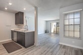 Located at 5601 E Orangethorpe Ave in Anaheim, CA, this single-floor unit offers a clean, modern aesthetic throughout. Light wood-style flooring runs continuously across the living spaces, complemented by neutral gray walls and textured ceilings that create a bright, cohesive interior.

The open living area is a standout feature, offering generous space and direct access to an outdoor balcony through a full-width sliding glass door that floods the room with natural light. A pass-through window connects the living area to the kitchen, enhancing the open feel. The kitchen is well-appointed with dark wood cabinetry, light quartz-style countertops, stainless steel appliances including a refrigerator, range, and microwave, plus recessed lighting overhead.

The bedrooms are well-proportioned, each featuring the same light wood flooring, neutral walls, and windows fitted with blinds that allow for natural light and privacy. One bedroom is served by a bathroom with a shower stall and curved curtain rod, while a second bathroom includes a full tub-shower combination with light wood flooring and a vanity with dark cabinetry. The layout flows intuitively, making the space functional and comfortable throughout.