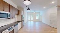 Located at 5111 Abercorn St in Savannah, GA, this well-appointed 2-bedroom, 2-bathroom single-floor residence offers a clean, contemporary design throughout. The open-concept kitchen and living area serves as the heart of the home, featuring stainless steel appliances, dark granite countertops, a white subway tile backsplash, and a mix of warm wood-toned upper cabinets with crisp white lower cabinetry. Stylish pendant lighting accents the space, which flows seamlessly into a bright, spacious living area with light hardwood-style flooring, a ceiling fan, and French doors that invite natural light and outdoor views. The bedrooms are carpeted for comfort, each offering generous proportions, large windows, ceiling fans, and access to well-organized closets with wire shelving systems. The primary bedroom includes a walk-in closet and an en-suite bathroom complete with a soaking tub, tiled shower surround, dark granite vanity, and direct closet access. A dedicated laundry room houses a full-size washer and dryer. Additional utility and storage spaces round out the functional layout, making this a thoughtfully designed and move-in-ready residence.
