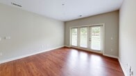 Located at 1015 Bolling Ave #104 in Norfolk, Virginia, this two-bedroom, two-bathroom residence offers a thoughtfully designed single-floor layout with a comfortable and functional living experience. The open-concept living, dining, and kitchen area serves as the heart of the home, featuring rich hardwood-style flooring and French doors that invite abundant natural light and provide access to an outdoor area with greenery views. The kitchen is well-appointed with dark espresso cabinetry, granite countertops, a tile backsplash, stainless steel appliances including a range, microwave, and refrigerator, and a peninsula with pendant lighting — ideal for both cooking and casual dining. Both bedrooms are carpeted and bright, each featuring windows with outdoor views and generous closet space. The spacious primary bedroom includes a walk-in closet with built-in wire shelving. The primary bathroom features a dual-sink vanity with dark cabinetry and tile flooring, while the secondary bathroom offers a walk-in shower with sliding glass doors and tile flooring. A dedicated laundry area adds everyday convenience. With six total closets throughout, storage is plentiful. The neutral color palette and clean finishes create a cohesive, move-in-ready atmosphere throughout the home.