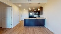 This single-floor residence offers a thoughtfully designed layout that balances comfort and functionality. The kitchen serves as the heart of the home, showcasing rich dark-espresso cabinetry, granite countertops, and a suite of black appliances including a refrigerator, range, and over-the-range microwave. A peninsula with a built-in sink and pendant lighting above creates a natural transition into the adjacent dining area, which features its own ceiling fan and a window that fills the space with natural light. Wood-style flooring flows seamlessly throughout the main living and kitchen areas, lending warmth and continuity to the open-concept design. The bedrooms offer a comfortable retreat, each equipped with ceiling fans and windows with blinds. One bedroom features plush carpeting and a closet with built-in shelving, while another is finished with the same wood-style flooring seen in the main living areas. The bathroom is clean and efficiently laid out, featuring a granite-topped dark vanity with an integrated sink, a large mirror, and a shower-tub combo with tile surround. Brushed nickel hardware and fixtures add a cohesive, modern touch throughout. Overall, the space presents a practical and inviting atmosphere with consistent finishes across every room.