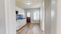 Located at 839 Farmington Ave in West Hartford, CT, this single-floor unit offers a well-maintained and thoughtfully updated living space. The kitchen serves as a standout feature, showcasing white shaker-style cabinetry, dark countertops, and a striking mosaic tile backsplash in shades of blue, gray, and white. White appliances including a gas range, refrigerator, and built-in microwave provide full functionality, while wood-look flooring and a classic wood entry door with window add character and warmth. Natural light filters in through multiple windows fitted with blinds. The living and bedroom areas are finished with warm, honey-toned hardwood floors that lend a timeless appeal throughout. Multiple windows in the bedroom spaces allow for generous natural light and views of the surrounding neighborhood, contributing to an airy and comfortable atmosphere. Radiator heating units are present throughout, reflecting the classic construction of the building. The bathroom is finished to a high standard, featuring large-format marble-look porcelain tile flooring, fully tiled walls around the tub and shower, a white vanity, and a window for natural ventilation. Overall, the space presents a clean, updated aesthetic that balances classic architectural elements with modern finishes.