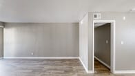 This single-story home offers a practical and comfortable layout across three bedrooms and three bathrooms. The living room is a welcoming, open space highlighted by wood-look plank flooring, neutral gray walls, crisp white trim, and a sliding glass door fitted with vertical blinds that invite natural light and provide outdoor access. A second living area features carpet flooring and a ceiling fan, adding a cozy touch. The kitchen is efficiently designed in a galley style, showcasing gray cabinetry, light countertops, a mosaic tile backsplash, and black stainless appliances including a refrigerator, range, and dishwasher. Each of the three bathrooms features a tiled tub-and-shower combination, a vanity with dark cabinetry, and wood-look flooring, maintaining a consistent and clean aesthetic throughout. The bedrooms are carpeted and generously proportioned, with the primary bedroom offering a comfortable retreat. Neutral taupe wall tones carry consistently through the home, creating a cohesive and calm atmosphere. A central hallway connects the rooms efficiently, and the overall layout, as seen from the dollhouse view, is compact yet well-organized for everyday living.