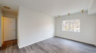 Located at 320 Grafton Ave in Dayton, Ohio, this single-floor unit has been thoughtfully updated with a clean, modern aesthetic. The living areas are finished with durable gray luxury vinyl plank flooring that runs consistently throughout, complemented by crisp white walls and bright gold flush-mount light fixtures that add a contemporary touch. Multiple windows allow natural light to fill the rooms, offering views of the surrounding neighborhood and mature trees. Each room presents a neutral, move-in-ready canvas with clean lines and well-maintained finishes. The kitchen features a standout design with two-tone cabinetry — white upper cabinets paired with gray lower cabinets — accented by brushed gold hardware and pulls. A marble-look quartz countertop adds a refined touch, while the deep stainless steel sink is equipped with a matching gold pull-down faucet, creating a cohesive and stylish workspace. The bathroom continues the gold hardware theme with a tub-shower combination, gold fixtures, and textured white walls that provide a clean, functional finish. The consistent use of gold accents across the kitchen, bathroom, and lighting ties the space together with a unified, modern design language throughout.