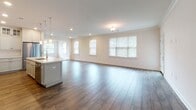 Located at 25 Mill St in Bernardsville, NJ, this single-floor residence offers a thoughtfully designed layout with modern finishes throughout. The open-concept living and dining area is bright and welcoming, featuring rich wood-look flooring, crown molding, recessed lighting, and multiple windows that invite natural light and provide a sense of openness.

The kitchen is a standout feature, showcasing white shaker-style cabinetry that extends to the ceiling with glass-front upper cabinets, a classic subway tile backsplash, and light stone countertops. A large central island with a light blue base provides ample workspace and is illuminated by elegant pendant lighting. Stainless steel appliances, including a gas range with a stainless hood and a refrigerator, complete this well-appointed kitchen.

The bedrooms are comfortably sized, each with wood-look flooring, crown molding, and natural light from windows with blinds. Generous walk-in closets with wire shelving systems offer abundant storage.

The bathrooms are finished with white shaker vanities, stone countertops, and brushed nickel fixtures. One bathroom features tile flooring, while another continues the wood-look flooring found throughout the home.

A dedicated laundry room houses a full-size washer and dryer alongside upper cabinetry for added storage. The space presents a clean, modern aesthetic with consistent, high-quality finishes from room to room.