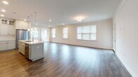 Located at 25 Mill St in Bernardsville, NJ, this single-floor residence offers a thoughtfully designed layout with modern finishes throughout. The open-concept living and dining area is bright and welcoming, featuring rich wood-look flooring, crown molding, recessed lighting, and multiple windows that invite natural light and provide a sense of openness.

The kitchen is a standout feature, showcasing white shaker-style cabinetry that extends to the ceiling with glass-front upper cabinets, a classic subway tile backsplash, and light stone countertops. A large central island with a light blue base provides ample workspace and is illuminated by elegant pendant lighting. Stainless steel appliances, including a gas range with a stainless hood and a refrigerator, complete this well-appointed kitchen.

The bedrooms are comfortably sized, each with wood-look flooring, crown molding, and natural light from windows with blinds. Generous walk-in closets with wire shelving systems offer abundant storage.

The bathrooms are finished with white shaker vanities, stone countertops, and brushed nickel fixtures. One bathroom features tile flooring, while another continues the wood-look flooring found throughout the home.

A dedicated laundry room houses a full-size washer and dryer alongside upper cabinetry for added storage. The space presents a clean, modern aesthetic with consistent, high-quality finishes from room to room.