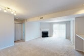 This 2-bedroom, 2-bathroom single-floor residence at 1109 Olive Lake Dr in Olivette, MO offers a well-organized layout designed for comfortable everyday living. The open living room is a standout space, featuring a wood-burning fireplace with a classic white mantel and a large sliding glass door fitted with vertical blinds that flood the room with natural light and provide access to an outdoor area. Plush wall-to-wall carpeting runs throughout the living areas and bedrooms, contributing to a warm, comfortable atmosphere. The kitchen is efficiently designed in a U-shape, outfitted with rich dark cabinetry, light countertops, and black appliances including a range, microwave, refrigerator, and dishwasher. Wood-look flooring anchors the kitchen, which opens to the living area via a convenient pass-through counter. The primary bedroom is generously proportioned, featuring a mirrored closet door and carpet flooring. The second bedroom is equally well-lit, with a large window overlooking greenery and a track light fixture overhead. Both bathrooms are clean and functional, with one featuring a tub/shower combo with chrome fixtures and wood-look flooring. Three hallways and two closets provide practical storage throughout the home.