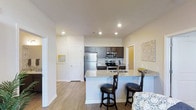 This well-appointed 2-bedroom, 2-bathroom residence is thoughtfully designed across a single floor, offering a seamless blend of style and functionality. The open-concept layout connects the kitchen and living areas, creating an inviting and spacious atmosphere ideal for both everyday living and entertaining.

The kitchen is a standout feature, showcasing dark espresso cabinetry that contrasts beautifully with light granite countertops. A breakfast bar with seating for two provides a casual dining option, while stainless steel appliances — including a refrigerator, microwave, and range — add a sleek, modern touch. Recessed lighting illuminates the space effectively, enhancing its clean, contemporary feel.

Durable wood-style flooring flows throughout the main living areas, contributing warmth and a cohesive aesthetic. The neutral color palette of soft whites and warm tones creates a bright, airy ambiance that feels both welcoming and versatile. Thoughtful details such as decorative wall art and natural light from multiple openings further elevate the overall character of the space.

With two well-sized bedrooms and two full bathrooms, this residence offers comfortable accommodations suitable for a range of lifestyles, all within a polished, move-in-ready layout.