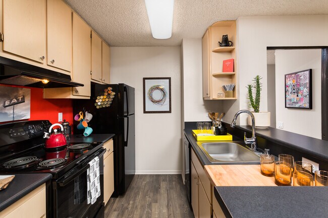 Cocina del paquete clásico II con electrodomésticos negros, encimeras de laminado negro, gabinetes de roble y pisos de superficie dura. - AVA Pacific Beach