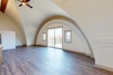 Located at 870 Westminster St in Providence, Rhode Island, this architecturally striking 2-bedroom, 1-bathroom residence immediately captivates with its dramatic vaulted arched ceilings — a defining design element that lends the main living area a sense of grandeur and openness rarely found in urban residences. Sweeping curved archways frame the space beautifully, drawing the eye upward while a ceiling fan adds practical comfort. Rich hardwood-style flooring flows throughout, complementing the bright, neutral palette.

The living area opens directly onto a private balcony through sliding glass doors, allowing abundant natural light to pour in while offering views of the surrounding Providence cityscape. The kitchen is thoughtfully appointed with light wood cabinetry, white subway tile backsplash, a full suite of stainless steel appliances including a range, microwave, dishwasher, and refrigerator, and clean countertops.

Both bedrooms are well-proportioned, with the primary bedroom offering generous closet space and vaulted architectural detailing. Two closets throughout the residence provide ample storage. The bathroom features a glass-enclosed walk-in shower with a clean, modern finish. The overall ambiance is one of unique character, contemporary finishes, and thoughtful design.